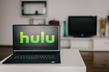 An image featuring Hulu on laptop while TV streaming in the background concept