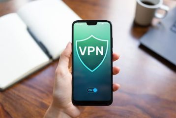 An image featuring a person holding his phone and using a VPN at the same time