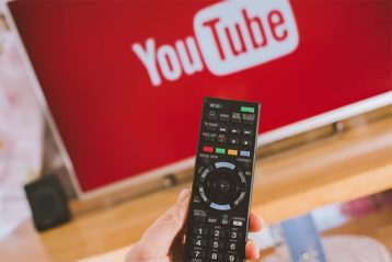 An image featuring a person holding their remote control and using YouTube TV on TV concept