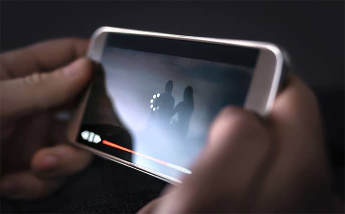 An image featuring a person watching a video on their mobile phone while the video is buffering concept