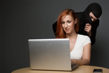 An image featuring a thief standing behind a woman's back representing identity theft from behind concept