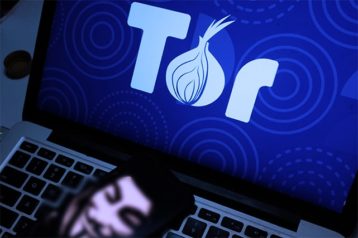 An image featuring Tor browser opened on laptop with anonymous mask on the bottom