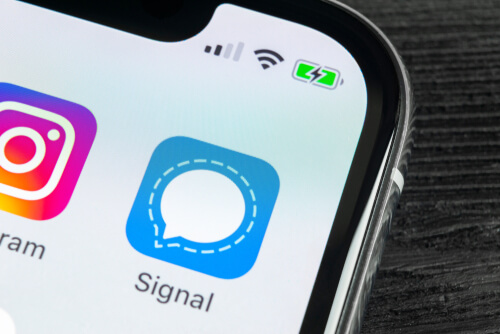 an image of the signal application showcased on an iphone device's screen in a blue color with a white chat bubble in the middle and an outline