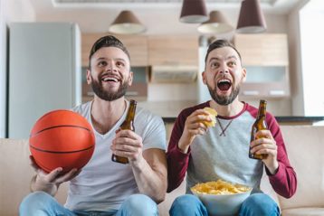 An image featuring two people drinking beer and holding a basketball representing them watching the NBA concept