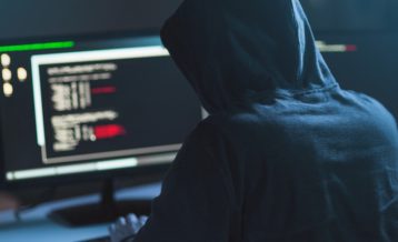 An image of a hacker sitting in front of a desktop monitor coding in Linux