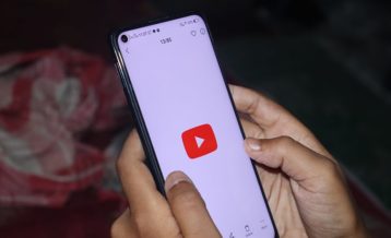 an image of a person using an Android phone with a camera cutout on the top left corner running the YouTube application