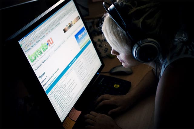 An image of a girl interacting with a torrent website while wearing headphones