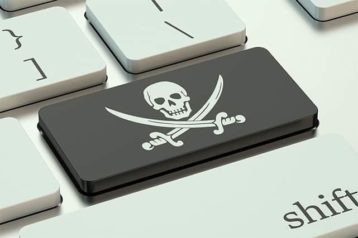 An image featuring a keyboard with the enter button replaced with a black background and a white skull with knifes inside of it representing piracy