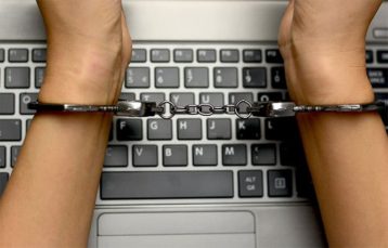 An image featuring a person in handcuffs with his laptop representing torrenting jail