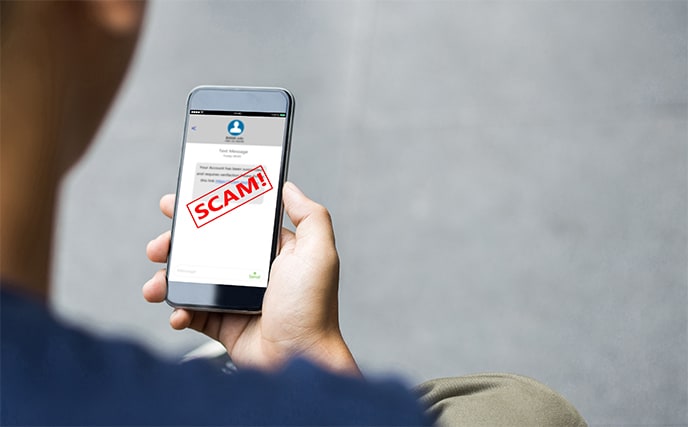 An image featuring a person holding his mobile phone that has SMS scam on it concept