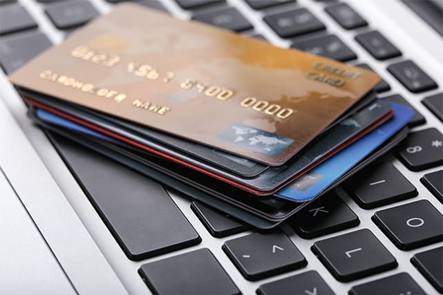 An image featuring credit and payment cards on top of a laptop