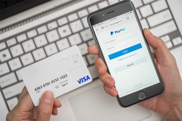 an image with person holding smartphone with PayPal account and credit card 