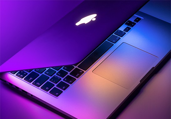 An image featuring a MacBook pro on desk with blue and purple lights concept