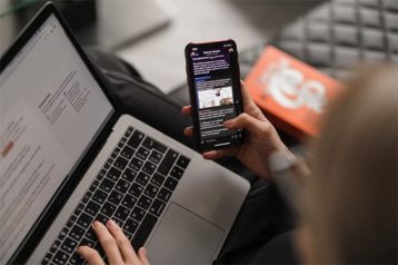 An image featuring a person using his phone and laptop concept